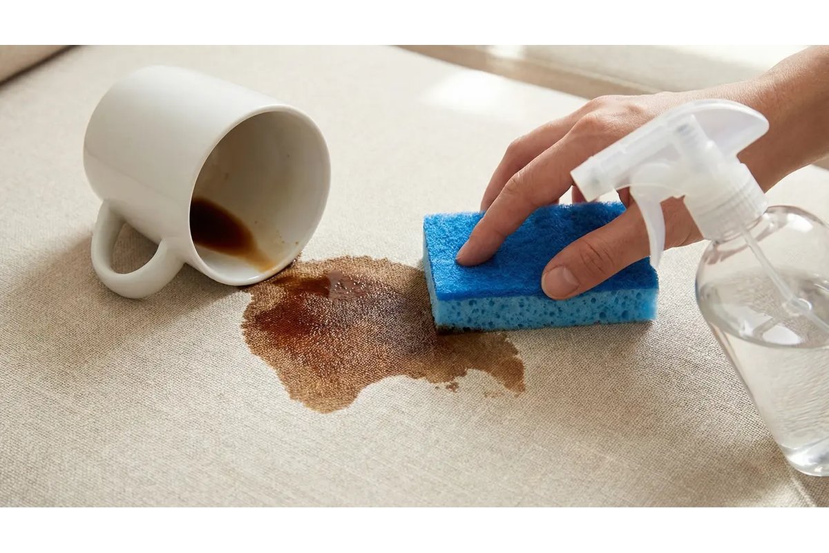 Macchia di caffè su un tappeto chiaro con una tazza rovesciata.