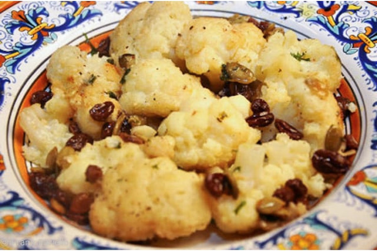 Cavolfiore fresco su un tagliere di legno con coltello.