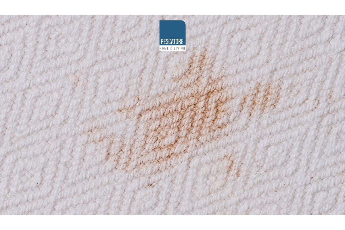 Macchia di ruggine su tessuto bianco vicino a prodotti per la pulizia.