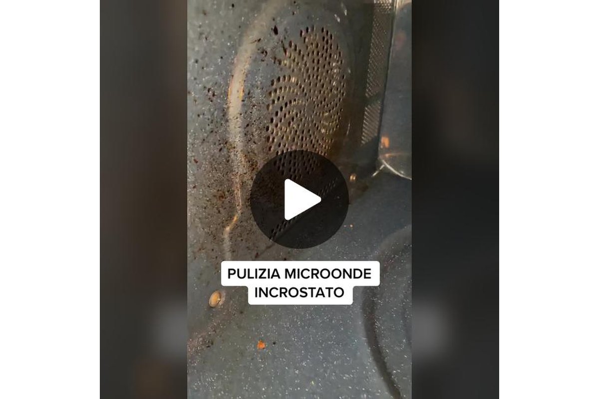 Donna pulisce microonde con un panno umido.