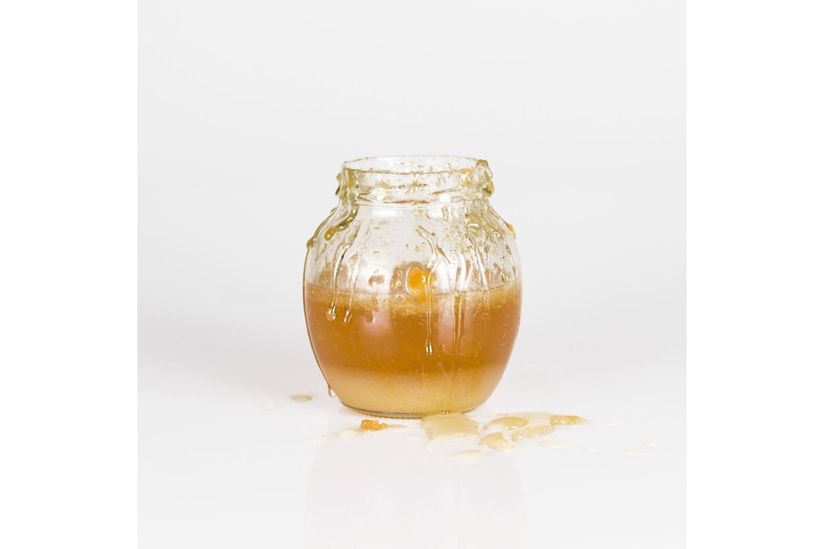 Barattoli di miele cristallizzato su uno scaffale in legno.