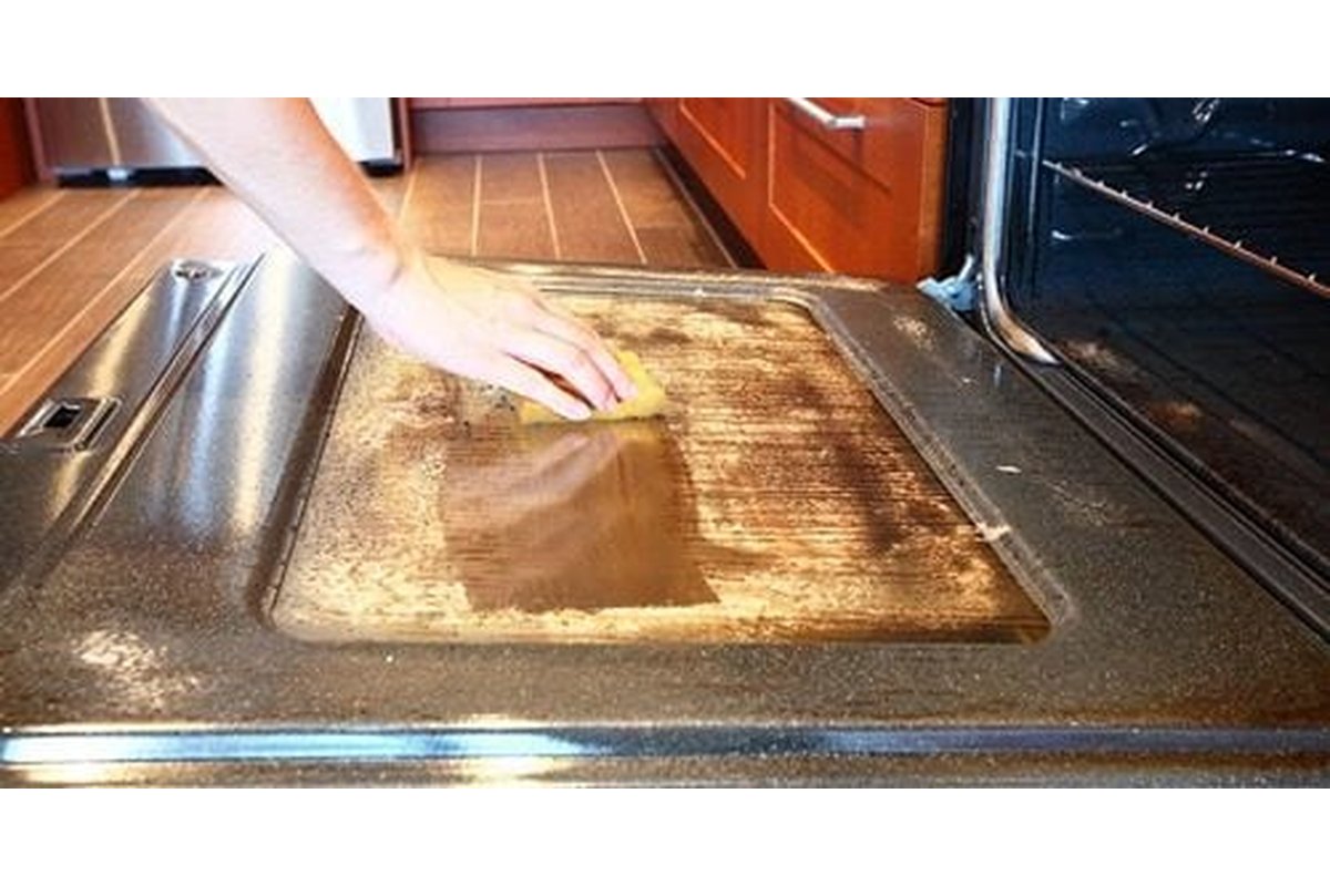 Porta del forno incrostata con prodotti per la pulizia fatti in casa.