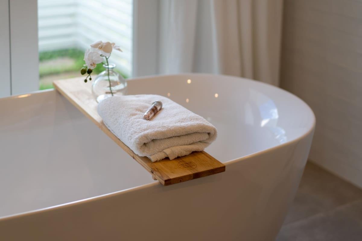 Donna che pulisce una vasca acrilica con un panno morbido.